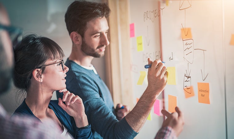 a man and woman writing on a white board
