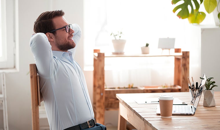 a man with glasses and a white shirt leaning over a table with a coffee cup on it